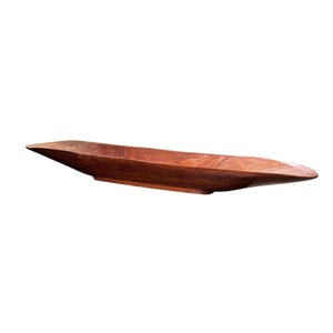 Könnte beinhalten: Eine lange Servierschale aus Holz mit einer satten, rotbraunen Oberfläche. Die Schale hat eine flache, bootsartige Form mit spitzen Enden und sanft geschwungenen Seiten. Die Holzmaserung ist sichtbar.