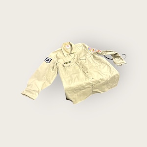 Op de afbeelding: Kaki-kleurig button-down shirt met lange mouwen, twee borstzakken en patches op de mouwen. Het shirt heeft een kraag en een kleine rechthoekige patch boven de linker borstzak. Het shirt is gemaakt van een duurzame stof.