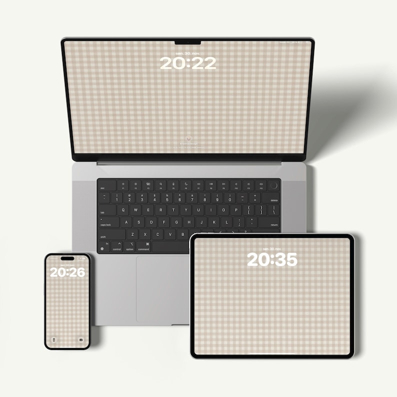 Pode incluir: Um port&aacute;til prateado, um tablet e um smartphone dispostos juntos. Cada ecr&atilde; exibe um papel de parede com padr&atilde;o vichy bege e branco com um rel&oacute;gio digital que mostra 20:22 no port&aacute;til, 20:35 no tablet e 20:26 no telem&oacute;vel.