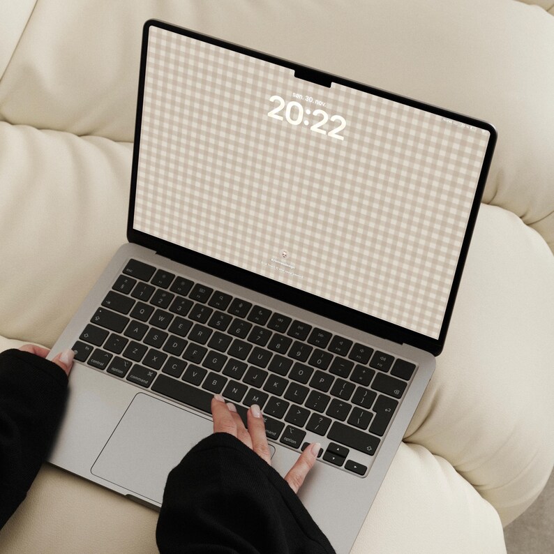 Pode incluir: Um port&aacute;til prateado com teclado preto e um ecr&atilde; que exibe um fundo com padr&atilde;o de xadrez vichy bege e branco. O ecr&atilde; mostra a hora 20:22 e a data em texto branco. O dispositivo apresenta uma moldura fina e um layout de teclado QWERTY.