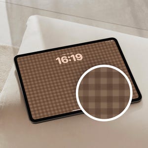 May include: A tablet displaying a brown and beige gingham pattern wallpaper with the time 16:19 and date text visible on the screen. A circular inset shows a magnified view of the checkered pattern, highlighting the brown and beige colour scheme.