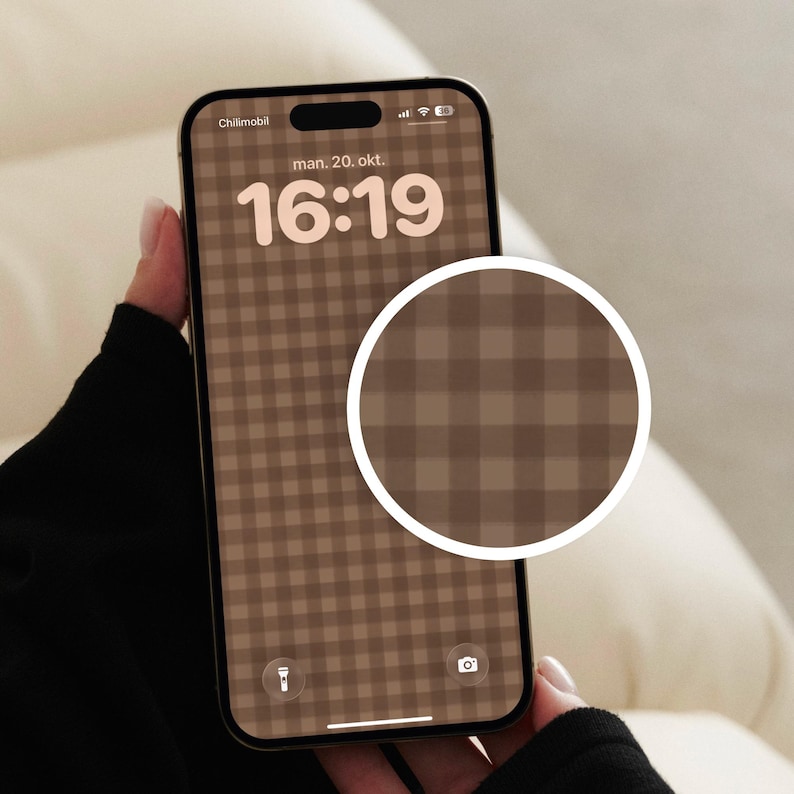 May include: A smartphone displaying a brown and beige gingham check pattern as a digital wallpaper. The screen shows the time 16:19 and the date man. 20. okt. A circular inset highlights a magnified view of the checkered pattern design.