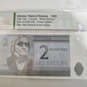 Puede incluir: Un billete de 2 coronas estonias de 1992, con un retrato de un hombre y el texto "Eesti Pank". El billete está calificado y encerrado en una funda protectora. El número de serie es AD 4237026.