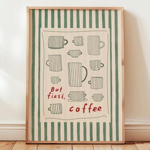May include: A framed art print with a cream-coloured background, featuring a collection of coffee mugs and the red text "But first, coffee". The print is bordered by green vertical stripes, adding a decorative touch.