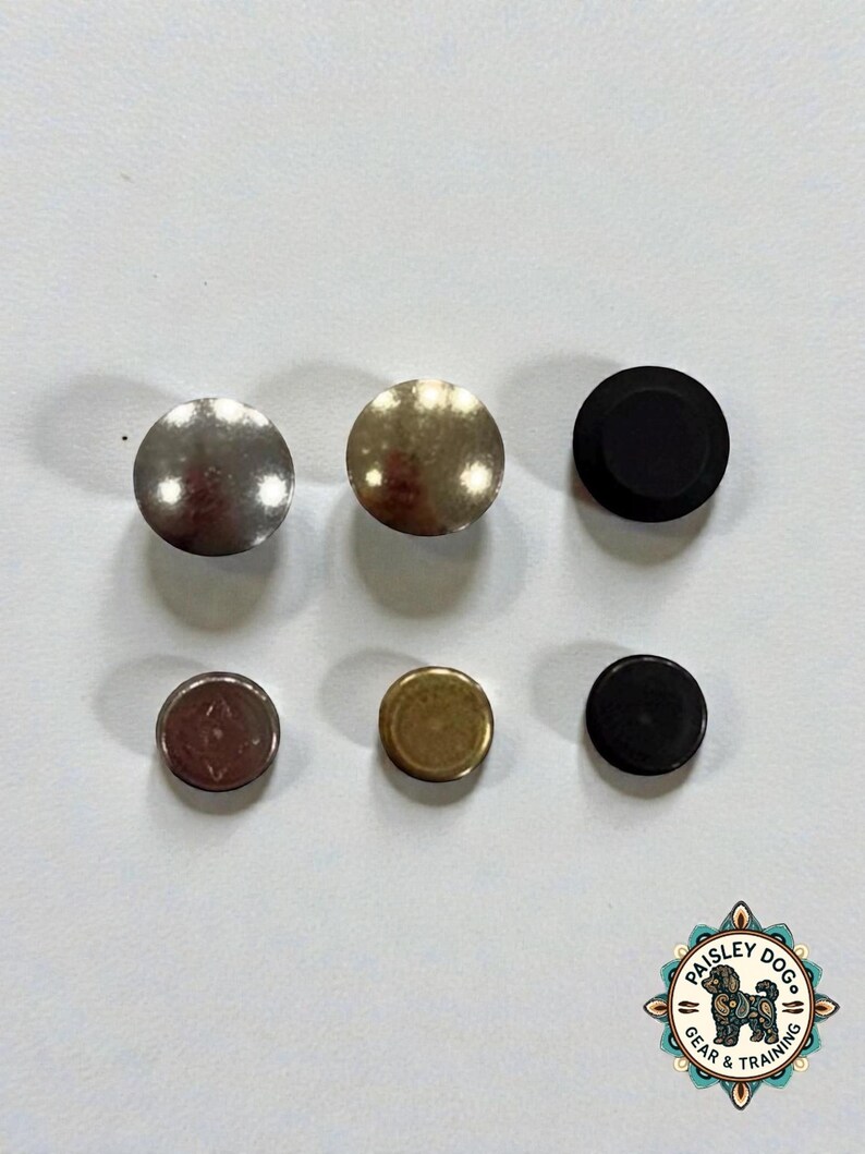 Puede incluir: Seis remaches met&aacute;licos circulares dispuestos en dos filas de tres. La fila superior presenta remaches m&aacute;s grandes en plata, lat&oacute;n y negro mate. La fila inferior contiene remaches a juego m&aacute;s peque&ntilde;os en plata, lat&oacute;n y negro mate. Hay un logotipo con un perro.