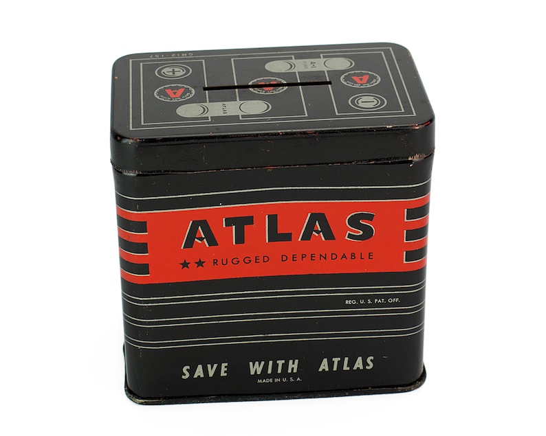 K&ouml;nnte beinhalten: Schwarze Metall-Sparb&uuml;chse mit einem rot-wei&szlig; gestreiften Design. Die Spardose hat einen Schlitz oben und tr&auml;gt die Aufschrift "ATLAS" in roten Buchstaben mit dem Text "RUGGED DEPENDABLE" darunter. Der Boden der Spardose tr&auml;gt die Aufschrift "SAVE WITH ATLAS" in wei&szlig;en Buchstaben.