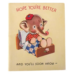 Puede incluir: Tarjeta vintage de recuperación con un elefante ilustrado en la cama. El elefante lleva una camisa roja de lunares y una flor en el pelo. La tarjeta dice "Hope You're Better" y "And You'll Soon Know".