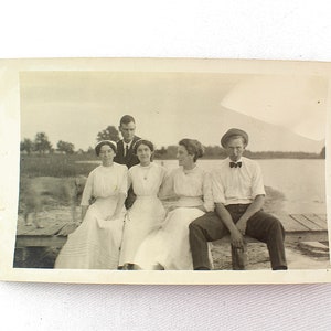 Carte postale photographique vintage RPPC Trois jeunes femmes en blanc Deux hommes sur la jetée