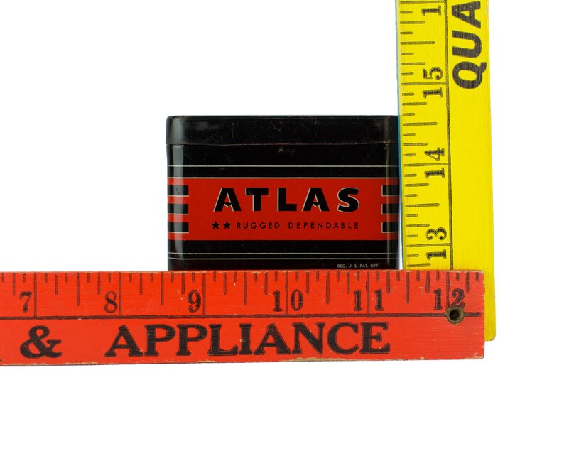 K&ouml;nnte beinhalten: Eine schwarze Metalldose mit einem rot-wei&szlig; gestreiften Design. Die Dose tr&auml;gt die Aufschrift "ATLAS" in wei&szlig;en Buchstaben und "RUGGED DEPENDABLE" in kleineren wei&szlig;en Buchstaben. Die Dose steht auf einem roten Holzlineal mit der Aufschrift "& APPLIANCE".