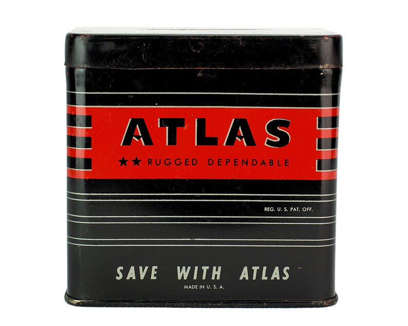 K&ouml;nnte beinhalten: Eine schwarze Metalldose mit roten und wei&szlig;en Streifen. Die Dose tr&auml;gt die Aufschrift "ATLAS", "RUGGED DEPENDABLE", "REG. U.S. PAT. OFF.", "SAVE WITH ATLAS" und "MADE IN U.S.A.".