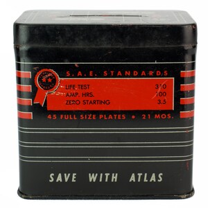 K&ouml;nnte beinhalten: Schwarze Metallbox mit roten und wei&szlig;en Streifen und dem Text "S.A.E. STANDARDS", "LIFE TEST", "AMP. HRS.", "ZERO STARTING", "45 FULL SIZE PLATES", "310", "100", "3.5", "21 MOS.", und "SAVE WITH ATLAS".