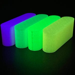 May include: Four elongated, rounded rectangular blocks arranged in a row, each emitting a distinct glow. The colors transition from a deep purple on the far left to a vibrant neon green on the far right, with two intermediate shades of lime green.