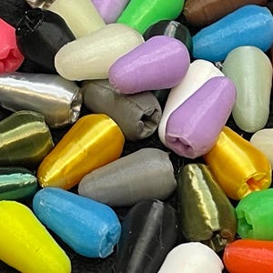 May include: A collection of colorful, teardrop-shaped objects in various colors including pink, yellow, green, and blue. The objects have a textured surface and a rounded base.