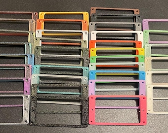 May include: A collection of rectangular drawer label holders in a variety of colors including red, yellow, orange, white, black, blue, green, purple, and pink. Each holder features a central horizontal bar and four small screw holes at the corners.