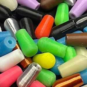 May include: A collection of colorful, cylindrical objects in various shades including green, red, black, and silver. The objects appear to be made of plastic or a similar material, with a smooth, rounded shape. The assortment is scattered, creating a visually diverse display.