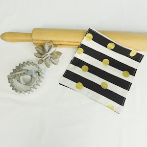 May include: A black and white striped fabric with gold polka dots, a wooden rolling pin, and two metal cookie cutters.