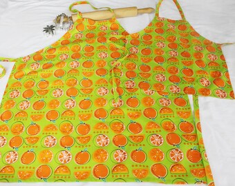 May include: Two green and orange kitchen aprons with a pattern of oranges on a green background.
