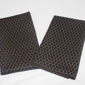 May include: Two black fabric napkins with a gold honeycomb pattern.
