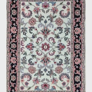 May include: Rectangular rug with a cream-colored field and an intricate floral pattern in pink, gray, and blue. The border is black with pink floral accents. The rug has a traditional, ornate design.
