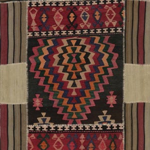 May include: A patchwork rug with a central geometric design in shades of orange, blue, and green on a black background. The rug features borders with red and cream-colored geometric patterns and striped sections.