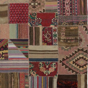 May include: A patchwork rug with a variety of patterns and colors. The rug is made up of many different pieces of fabric sewn together. The colors include red, pink, brown, beige, and blue. The rug has a vintage, bohemian style.
