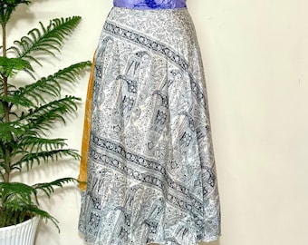 Puede incluir: Falda midi con estampado de cachemir en gris y blanco, combinada con una faja morada y un acento amarillo. La falda se exhibe en un maniquí negro. La falda mide aproximadamente 76 cm de largo.
