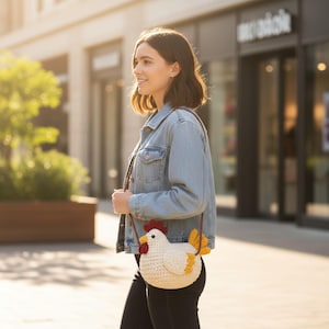 May include: A white crochet chicken-shaped crossbody bag with red, yellow, and black accents. The bag has a brown strap and is worn over the shoulder. The bag is a unique accessory.