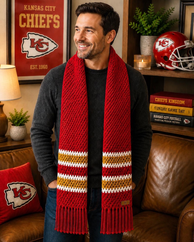 May include: A red and gold striped scarf with tassels. The scarf is worn by a person. The background includes a framed poster that says "Kansas City Chiefs" and a red cushion with the Chiefs logo.