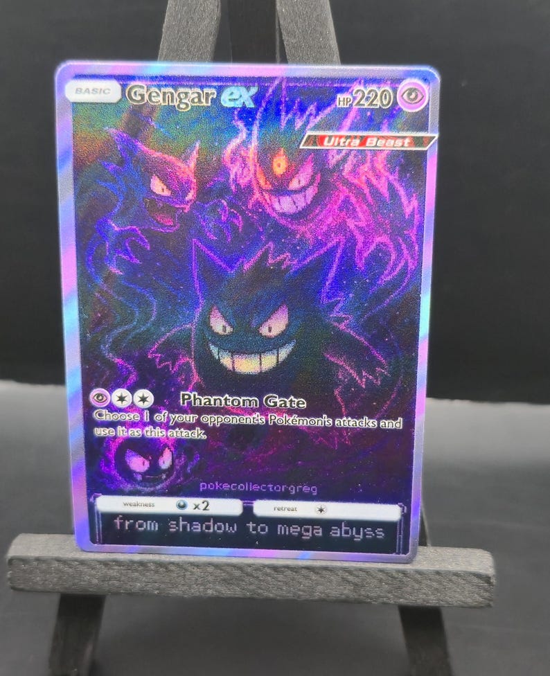 May include: A holographic Gengar ex Pok&eacute;mon trading card. The card features a purple and black illustration of Gengar with the text "Phantom Gate" and "from shadow to mega abyss". The card has a HP of 220 and is an Ultra Beast.