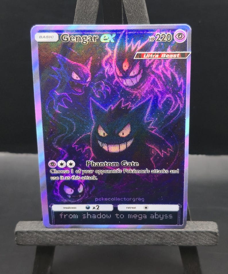 May include: A holographic Gengar ex Pok&eacute;mon trading card. The card features a purple and black illustration of Gengar and other Pok&eacute;mon characters. Text on the card includes "Gengar ex", "Phantom Gate", and "from shadow to mega abyss".