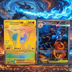 May include: Two collectible trading cards featuring Charizard. One card is gold with a Charizard illustration and the text "Mega Charizard X". The other card is blue with a black Charizard illustration. The background features a dragon and flames.