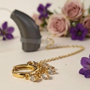 Oorbellen met een bevestigingsketting voor hoortoestellen. Sieraden voor cochleaire implantaten en hoortoestellen om verlies te voorkomen.