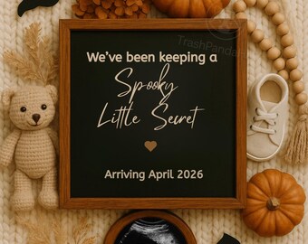 May include: A Halloween-themed pregnancy announcement. A wooden framed chalkboard reads "We've been keeping a Spooky Little Secret Arriving April 2026." The image includes pumpkins, a ghost, a bat, a teddy bear, and a sonogram.