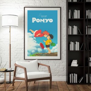 May include: Framed poster of the animated film "Ponyo." The artwork shows two children kissing against a blue sky with clouds. One child wears a yellow top and black shorts, holding a green bucket. The other child is in a red dress.