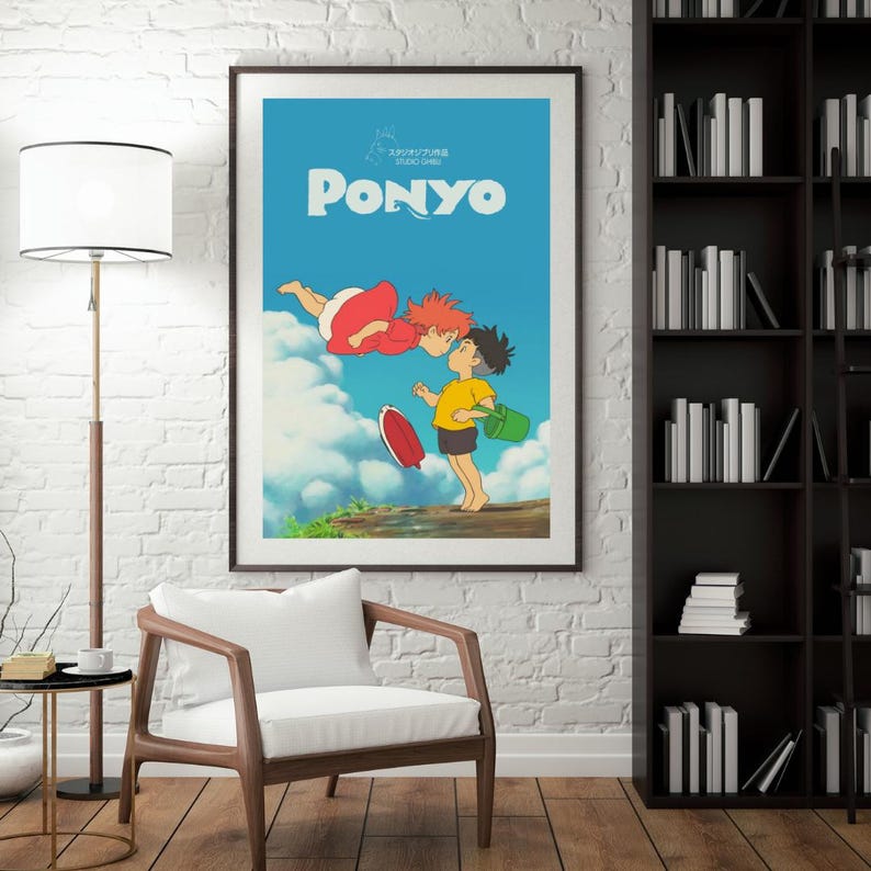 May include: Framed poster of the animated film "Ponyo." The artwork shows two children kissing against a blue sky with clouds. One child wears a yellow top and black shorts, holding a green bucket. The other child is in a red dress.