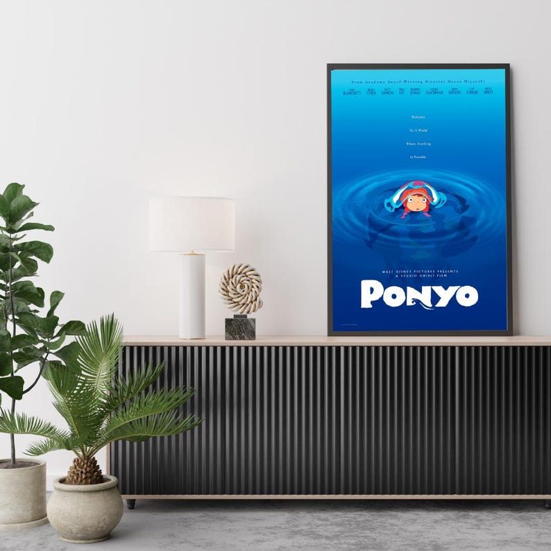 Puede incluir: P&oacute;ster enmarcado de la pel&iacute;cula de animaci&oacute;n "Ponyo". El p&oacute;ster presenta un fondo azul con una imagen central de un personaje en ondas de agua. El t&iacute;tulo "Ponyo" se muestra en blanco en la parte inferior.