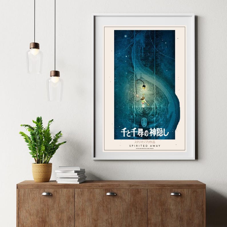 May include: Framed poster featuring a scene from "Spirited Away" with Japanese text. The artwork has a blue and teal color scheme, depicting a fantastical environment with characters and a lantern. The poster is in a white frame.
