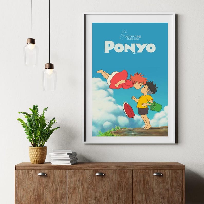 May include: A framed poster for the animated film "Ponyo." The image shows two characters kissing against a blue sky with clouds. The title "Ponyo" is written in white. The poster is in a white frame.