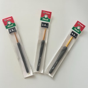 Peut inclure: Trois crochets dans un emballage transparent. Chaque crochet a un manche noir, un crochet doré et une étiquette indiquant la taille du crochet : 2,5 mm, 3,0 mm et 4,0 mm. L'emballage porte la marque "Tulip" et "MinD".