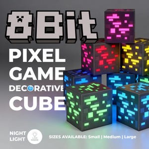 May include: A collection of black square decorative cubes featuring 8-bit pixelated patterns in glowing pink, red, yellow, green, and blue colours. The text 8Bit PIXEL GAME DECORATIVE CUBE and NIGHT LIGHT LED INSIDE are visible along with SIZES AVAILABLE: Small | Medium | Large.