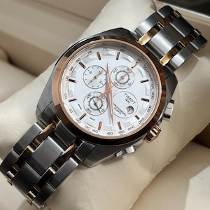 Op de afbeelding: Een Tissot chronograaf horloge met een witte wijzerplaat, roségouden bezel en een roestvrijstalen en goudkleurige armband. Het horloge heeft meerdere sub-wijzerplaten en de tekst "Tissot 1853 Chronograph Quartz".