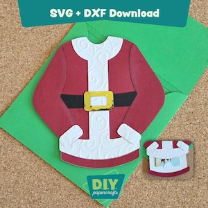 May include: A red and white Santa Claus suit cut-out with a black belt and gold buckle, placed on a green envelope. A smaller version of the suit is next to it. The text "SVG + DXF Download" is at the top, and "DIY papercrafts" is at the bottom.