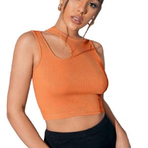May include: Orange ribbed crop top with a unique cutout detail on the neckline. The sleeveless top is paired with black bottoms. The top is made of a ribbed material.