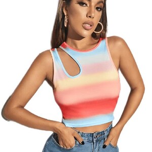 May include: A sleeveless crop top with a colorful horizontal striped pattern in shades of red, pink, yellow, and blue. The top has a unique asymmetrical neckline with a cutout detail. The model is wearing blue denim jeans with heart-shaped patches.