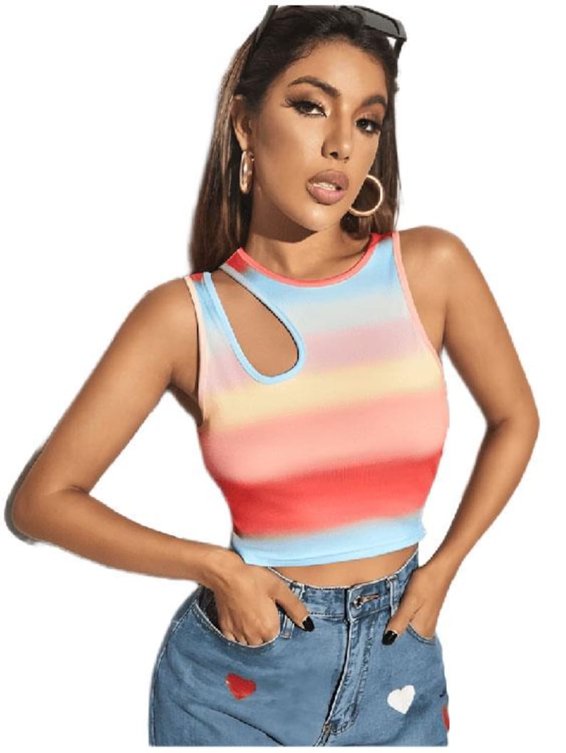 May include: A sleeveless crop top with a colorful horizontal striped pattern in shades of red, pink, yellow, and blue. The top has a unique asymmetrical neckline with a cutout detail. The model is wearing blue denim jeans with heart-shaped patches.