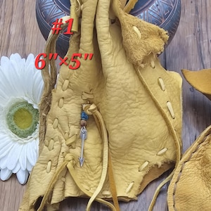 May include: A light brown leather pouch with a beaded arrow charm. The pouch is 6 inches by 5 inches and has a drawstring closure. #1