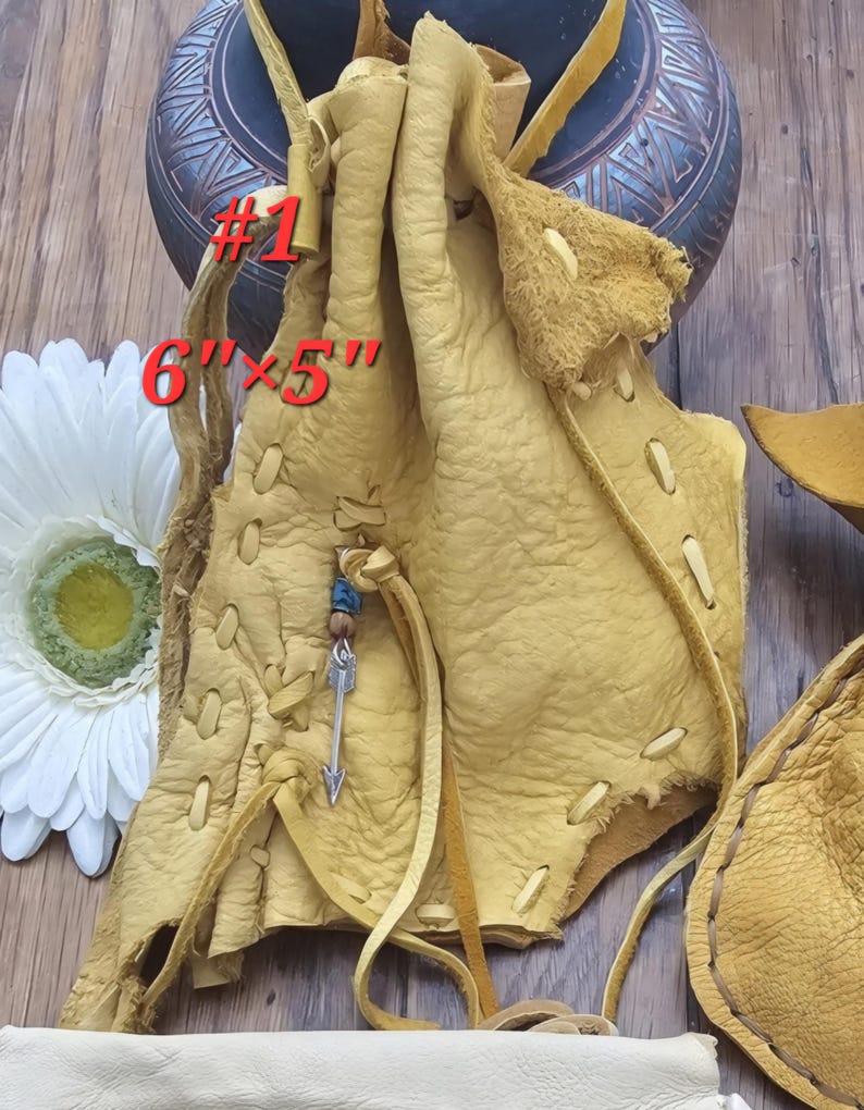 May include: A light brown leather pouch with a beaded arrow charm. The pouch is 6 inches by 5 inches and has a drawstring closure. #1