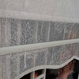 Könnte beinhalten: Cremefarbener Fenstervorhang mit einem filigranen Baumzweigmuster. Der Vorhang besteht aus einem transparenten, strukturierten Stoff, wobei sich das Design über die Paneele wiederholt. Der untere Rand ist mit einer gewellten Bordüre versehen.
