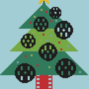 May include: A cross-stitch design of a Christmas tree with film reel ornaments and a yellow star on top. The tree is green with red, yellow, and blue accents. The trunk is red, and the background is light blue.