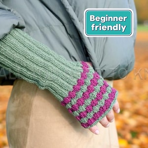 May include: Green and fuchsia knitted fingerless gloves. The gloves feature a ribbed design on the wrist and a textured pattern on the hand. The image includes a teal and white sign that says "Beginner friendly".